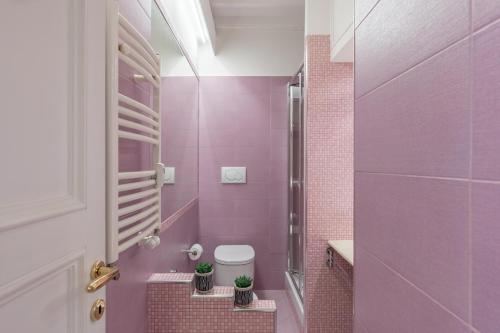 różowa łazienka z toaletą i różowymi kafelkami w obiekcie iFlat Via del Corso Elegant Apartment w Rzymie