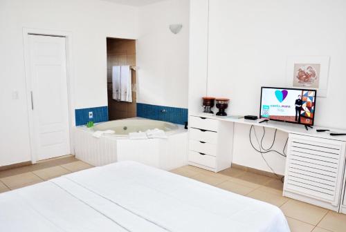 a white room with a tub and a bed in it at Bruno Marambaia Charme Hotel in Beberibe