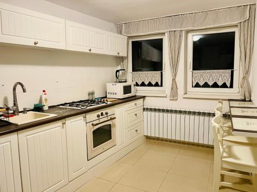 a kitchen with white cabinets and a stove top oven at Klimatyczny apartament z kominkiem in Toruń