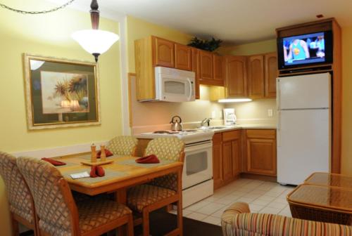 a kitchen with a table and a white refrigerator at Destin Holiday Beach Resort in Destin