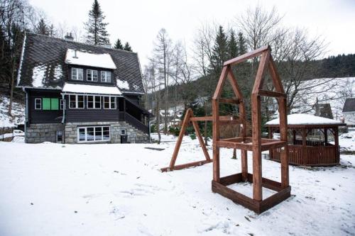 two swings in the snow in front of a house at Rakouská vila in Bělá pod Pradědem