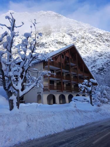 a building covered in snow in front of a mountain at Vénosc-Les 2 Alpes , Rez de jardin in Vénosc