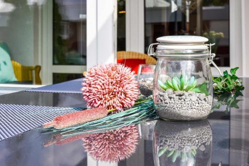 ein Glasgefäß mit Blumen auf dem Tisch in der Unterkunft Ferienhaus Inga in Bensersiel