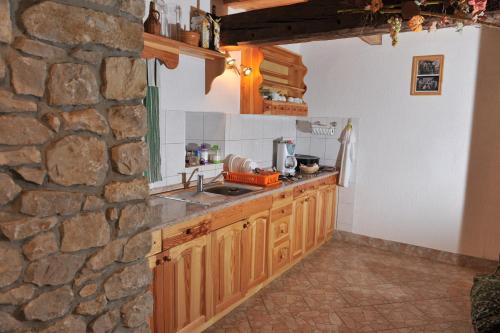 a kitchen with wooden cabinets and a stone wall at Vineyard Cottage Keglic in Šmarje pri Jelšah