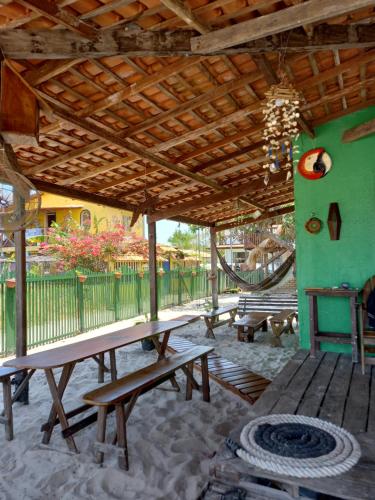 a patio with a wooden table and benches under a wooden roof at Algodoal Casa Verde in Maracanã
