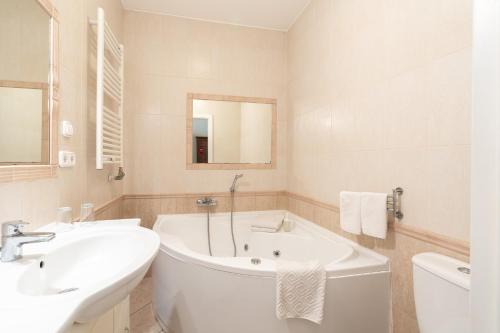 a white bathroom with a tub and a sink at Budapest Panorama Central in Budapest