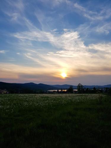 a field of grass with the sunset in the background at Domek Drwala k. Karpacza in Sosnówka