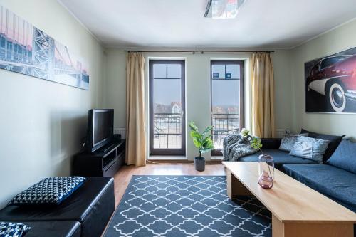 a living room with a blue couch and a tv at Panorama Apartment - Happy Hours in Sopot