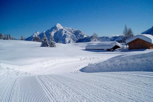 a snow covered mountain with a small building in the distance at Moosgut in Abtenau