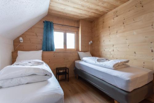 Ce lit se trouve dans un dortoir doté de murs en bois et d'une fenêtre. dans l'établissement Chalet les Vieux Murs, à L'Alpe-d'Huez