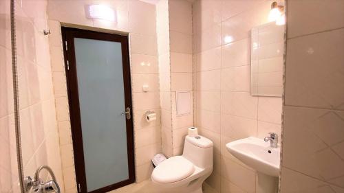 a white bathroom with a toilet and a sink at Prime Apartments in Bansko