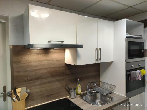a kitchen with white cabinets and a sink at Résidence Romains 0G in Strasbourg