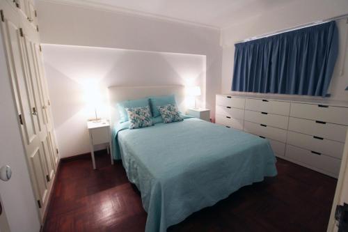 um quarto com uma cama com lençóis azuis e uma cómoda em Marina Mar Light by SAPvillas em Vilamoura