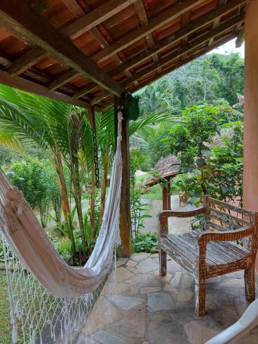 a porch with a hammock and a chair on a patio at Chalé Recanto Das Saíras em Paraty in Paraty