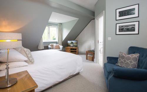 a bedroom with a white bed and a blue chair at Willowbeck Lodge Boutique Hotel in Carlisle