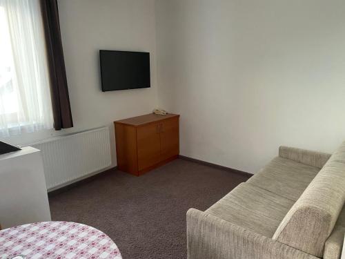 a room with a couch and a tv on the wall at Hotel Castel Latemar in Carezza al Lago