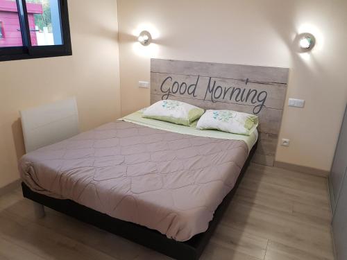 a bedroom with a bed with a good morning sign on it at Le Chalet de l'Authie in Saulchoy