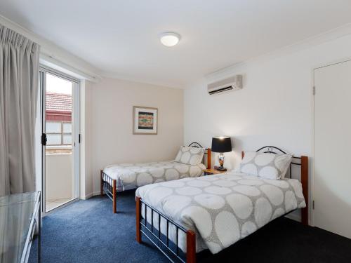 1 Schlafzimmer mit 2 Betten und einem Fenster in der Unterkunft Seashells, 1,21-23 Magnus Street - Unit with air con, wi-fi, complex pool and lift in Nelson Bay