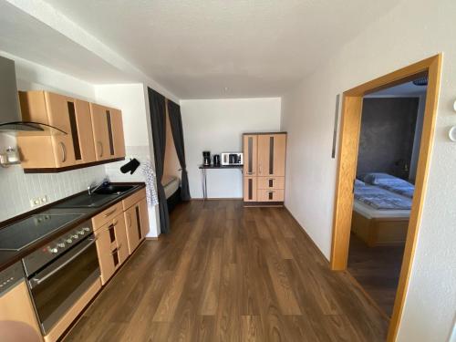 een keuken met houten vloeren en een kamer met een bed bij Ferienwohnung am Hillestausee in Winterberg