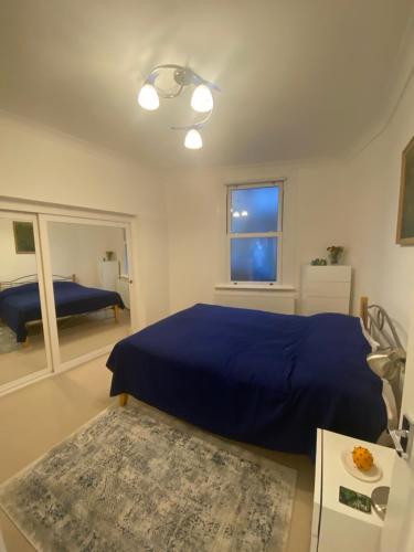 a bedroom with a blue bed and a window at Lovely Entire 1 Bedroom Flat with Patio in Chiswick in London