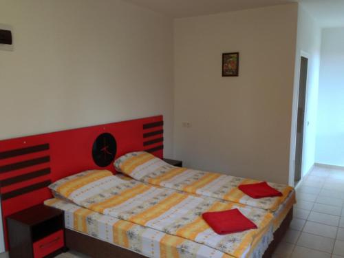a bedroom with a bed with a red headboard at Zapovedni Rai in Primorsko