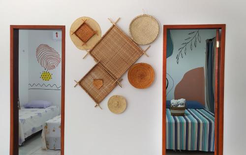 a room with straw hats on the wall and a mirror at Casinha de Sapê in Santo Amaro