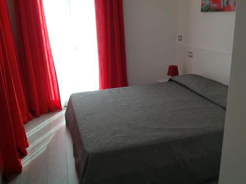 sypialnia z łóżkiem z czerwonymi zasłonami i oknem w obiekcie Appartamenti Villa Padania w mieście Malcesine