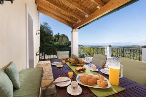 einen Tisch mit Teller mit Lebensmitteln auf einer Terrasse in der Unterkunft Agallis Corfu Residence in Sokrákion