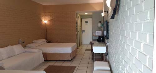 a hotel room with two beds and a couch at Angra dos Reis Flat Suíte no Portogalo in Angra dos Reis
