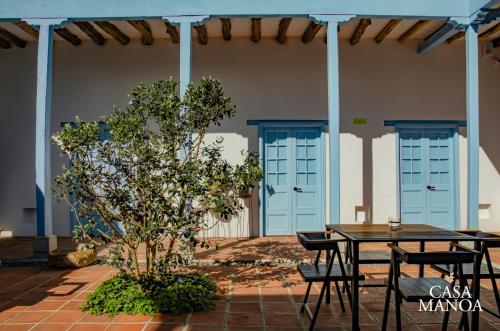 un patio con mesa, sillas y puertas azules en Casa Manoa en Sesquilé