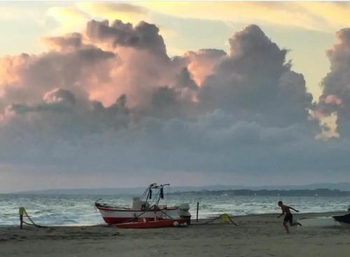 a man walking on the beach with a boat on the beach at SWEET HOME LULLABY - free parking in Passoscuro