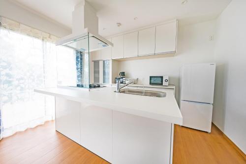 a white kitchen with a sink and a refrigerator at Villa Capri Miyakojima in Miyako-jima