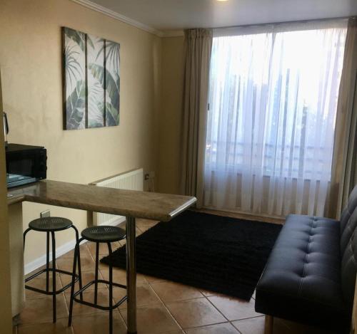 a living room with a table and two bar stools at EcoApart Concepción in Concepción