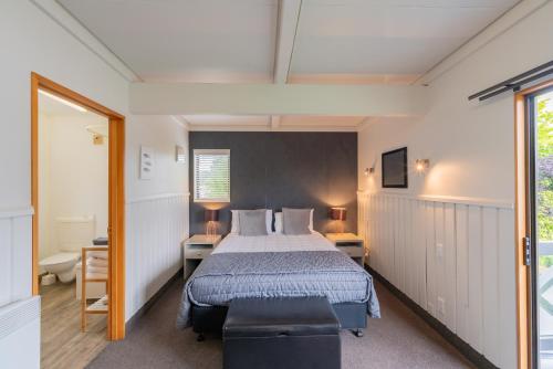 a bedroom with a bed and two tables and a window at ASURE Explorer Motel & Apartments in Te Anau