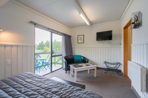 a hotel room with a bed and a balcony at ASURE Explorer Motel & Apartments in Te Anau