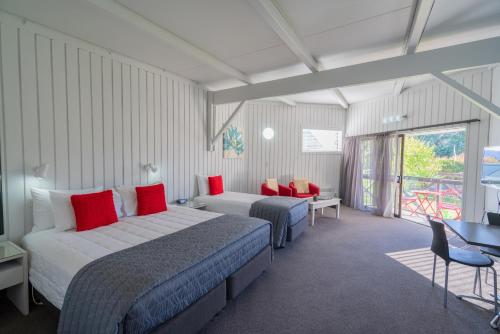 a hotel room with two beds and a table and chairs at ASURE Explorer Motel & Apartments in Te Anau