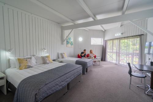 two people sitting in a hotel room with two beds at ASURE Explorer Motel & Apartments in Te Anau