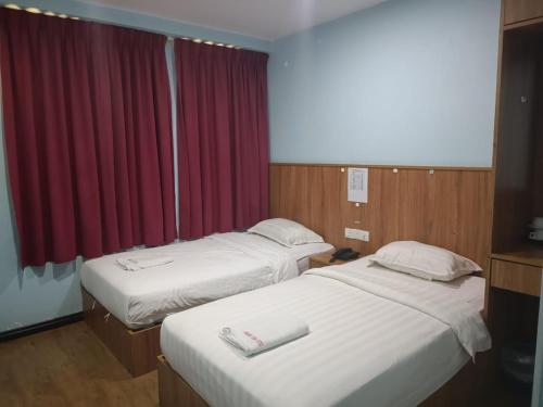ein Hotelzimmer mit 2 Betten und einem roten Vorhang in der Unterkunft AMBASSADOR LABUAN VIEW HOTEL in Victoria