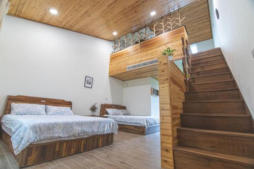 a bedroom with two beds and a staircase at Hakka Eco-farm 雅歌園民宿食農教育有機農場 in Wanluan