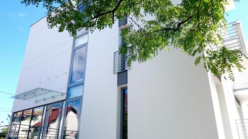 a white building with a tree in front of it at Willa Długa No. 4 Bed & Breakfast in Gdynia