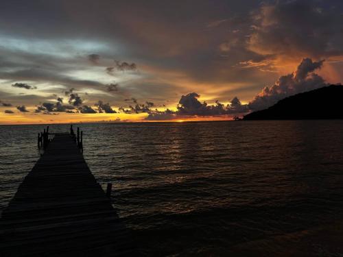a pier on the water with a sunset at Lazy Beach in Koh Rong Sanloem