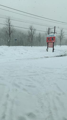 a snow covered field with a red sign in the middle at ビジネスホテル幸楽 in Abashiri