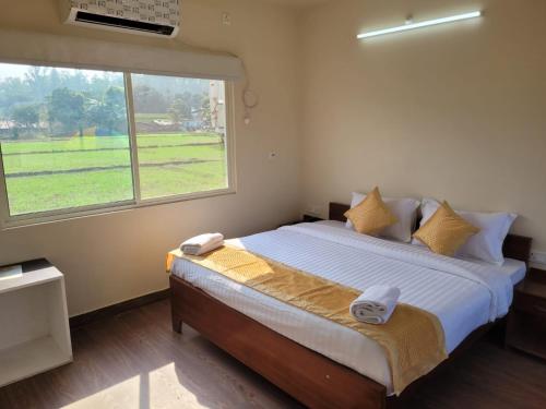 a bedroom with a large bed with a large window at Corbett VEDA INN in Rāmnagar