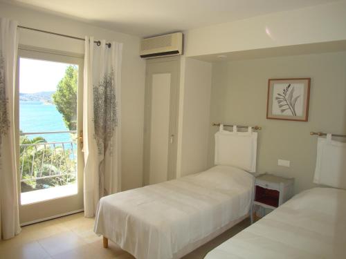 une chambre avec deux lits et une grande fenêtre dans l'établissement Farniente, au Lavandou