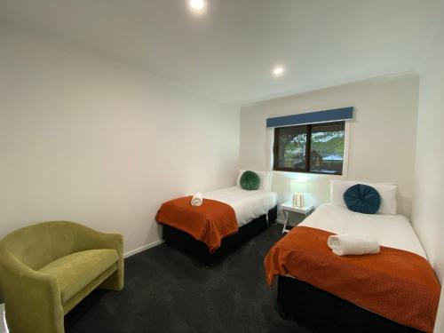 a hotel room with two beds and a chair at Motuoapa Bay Chalets in Turangi