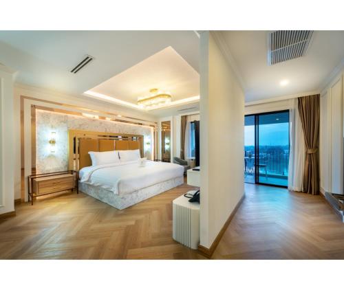 a bedroom with a white bed and a large window at Nine River Hotel in Ratchaburi