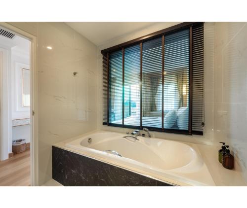 a bath tub in a bathroom with a window at Nine River Hotel in Ratchaburi
