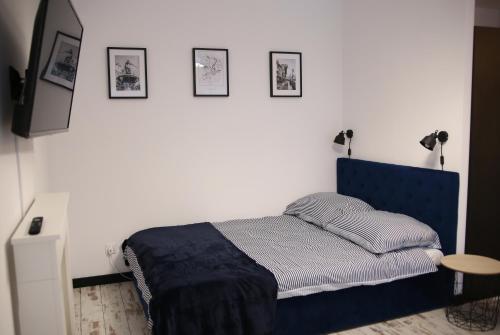 a bedroom with a blue bed and pictures on the wall at P&K Motlawa Apartment in Gdańsk