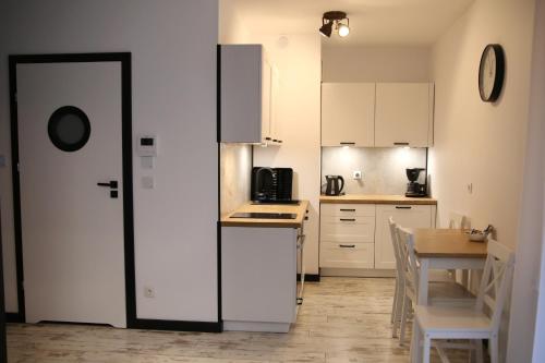 a kitchen with white cabinets and a table with chairs at P&K Motlawa Apartment in Gdańsk