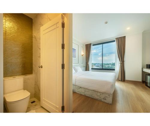 a bedroom with a bed and a bathroom with a window at Nine River Hotel in Ratchaburi